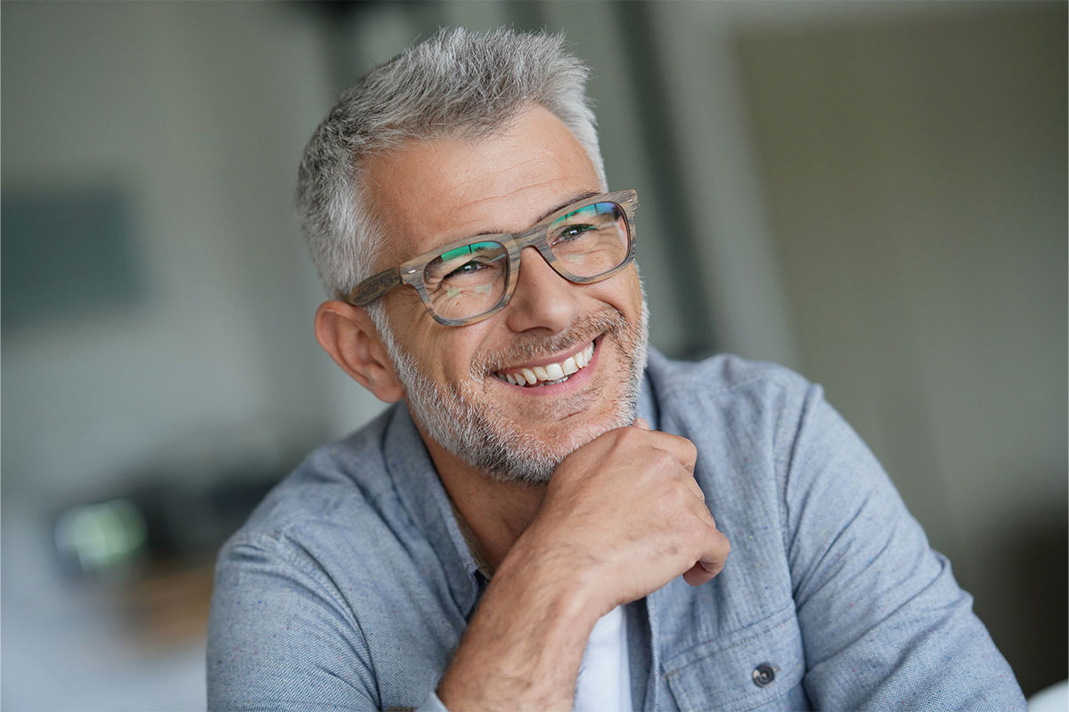 Uomo con capelli grigi e occhiali mentre sorride